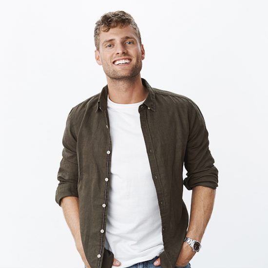 Relaxed, friendly good-looking european guy with bristle smiling joyfully with white healthy teeth holding hands in pockets being happy and satisfied, posing cheerfully over white background.
